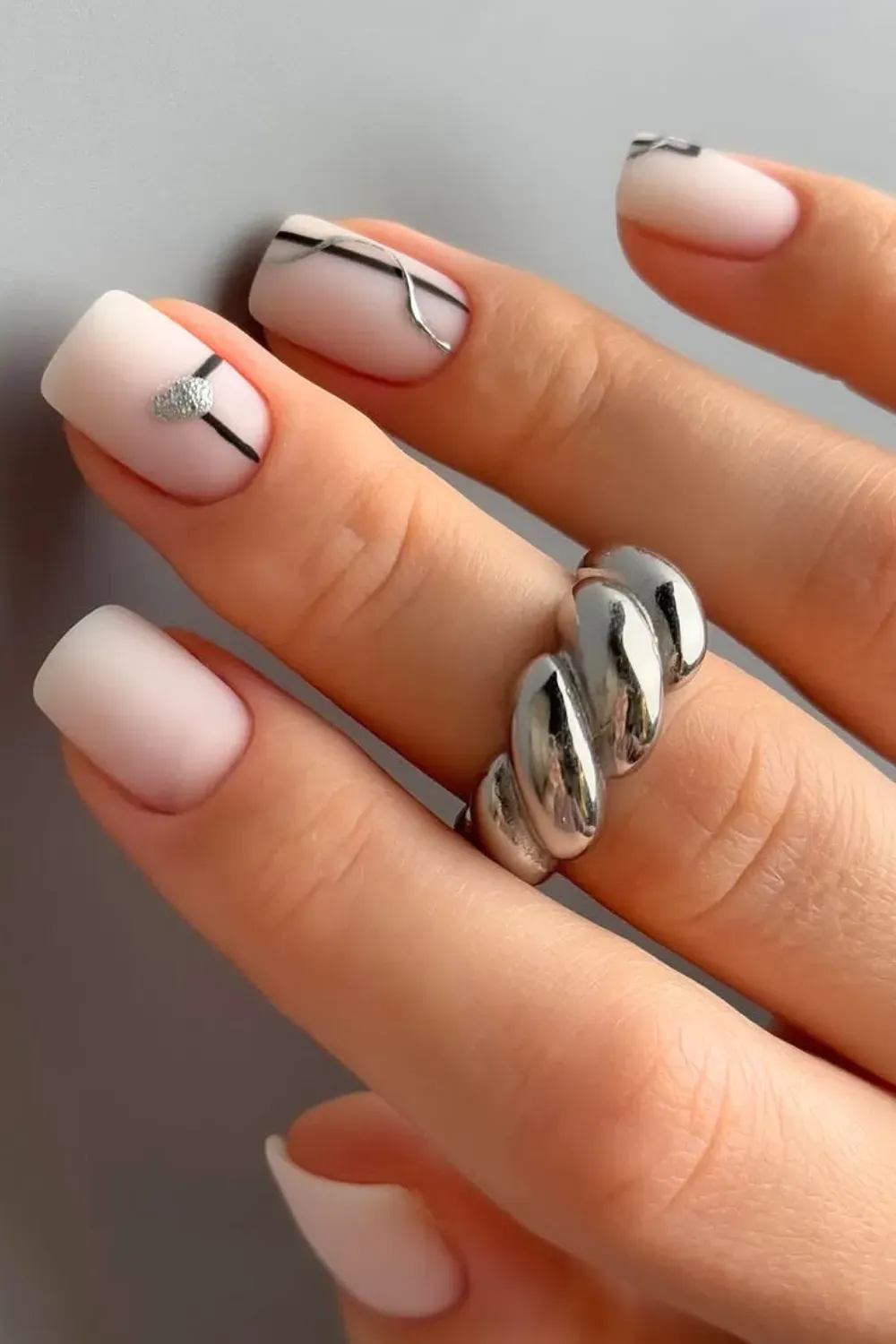 Modern geometric black and silver nail art on matte short nails.