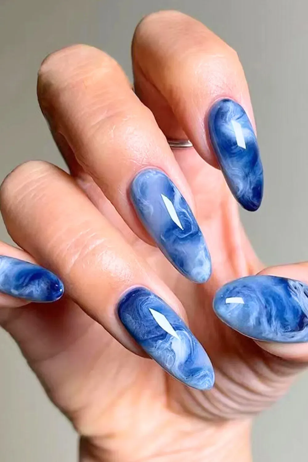 Swirling blue marble nails with a glossy finish, offering a sophisticated and chic look perfect for any occasion