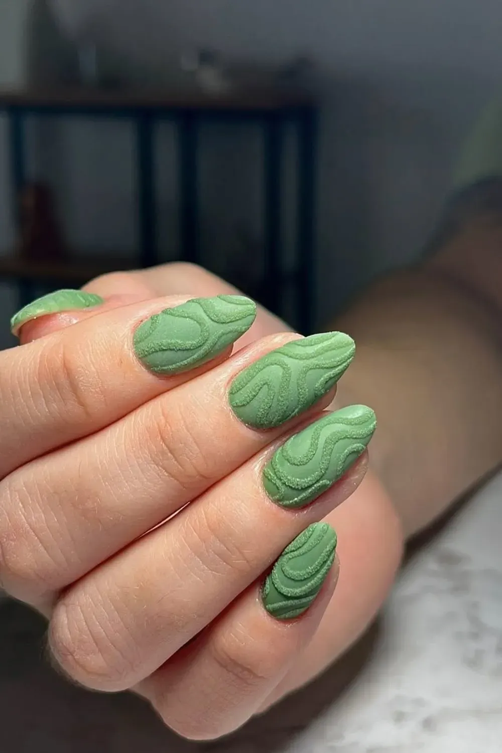 Matte green nails featuring sculpted, textured patterns for a unique and modern look