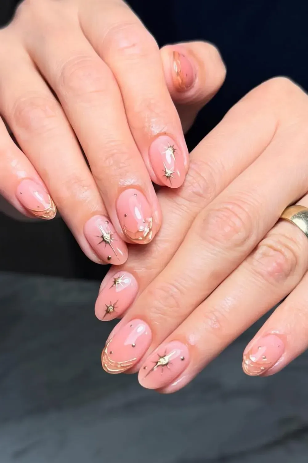 Soft neutral nails with small golden star embellishments for a celestial look.