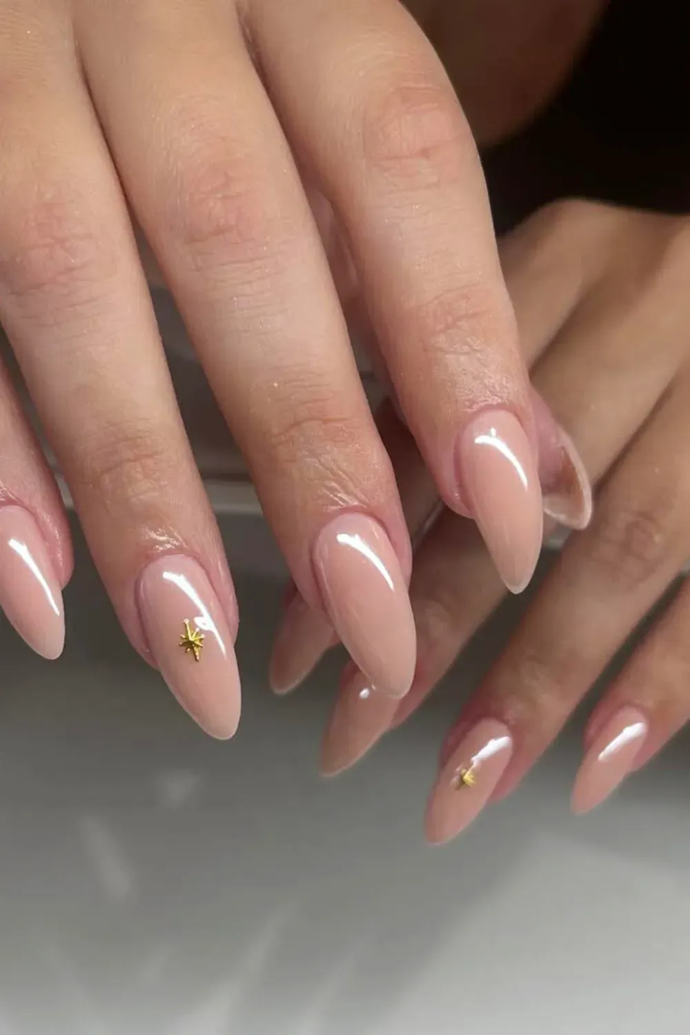 Nude nails with small golden star embellishments, offering a subtle, celestial look.