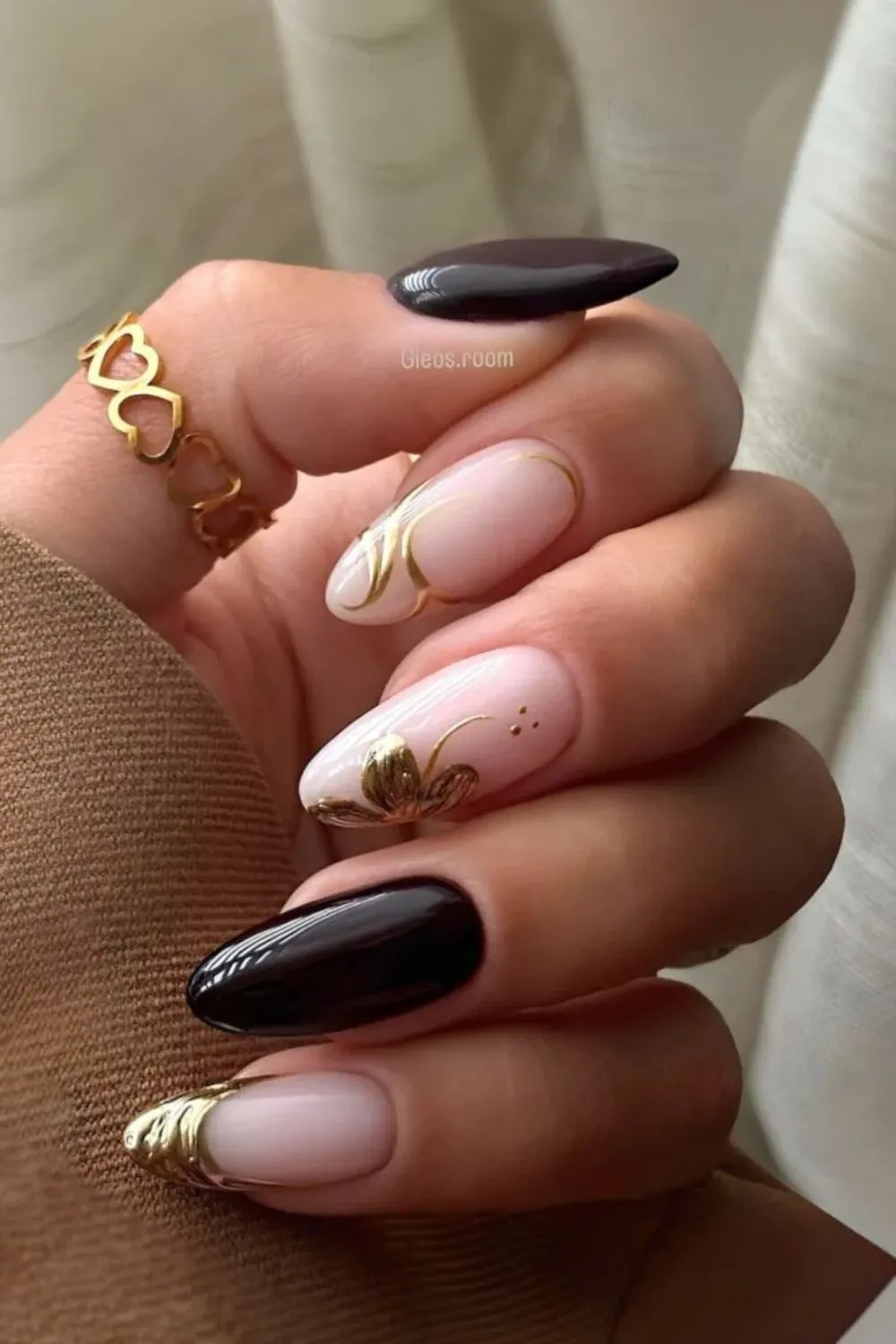 Black and Gold Chrome Floral Nails - Close-up of almond-shaped black nails with gold chrome floral accents.