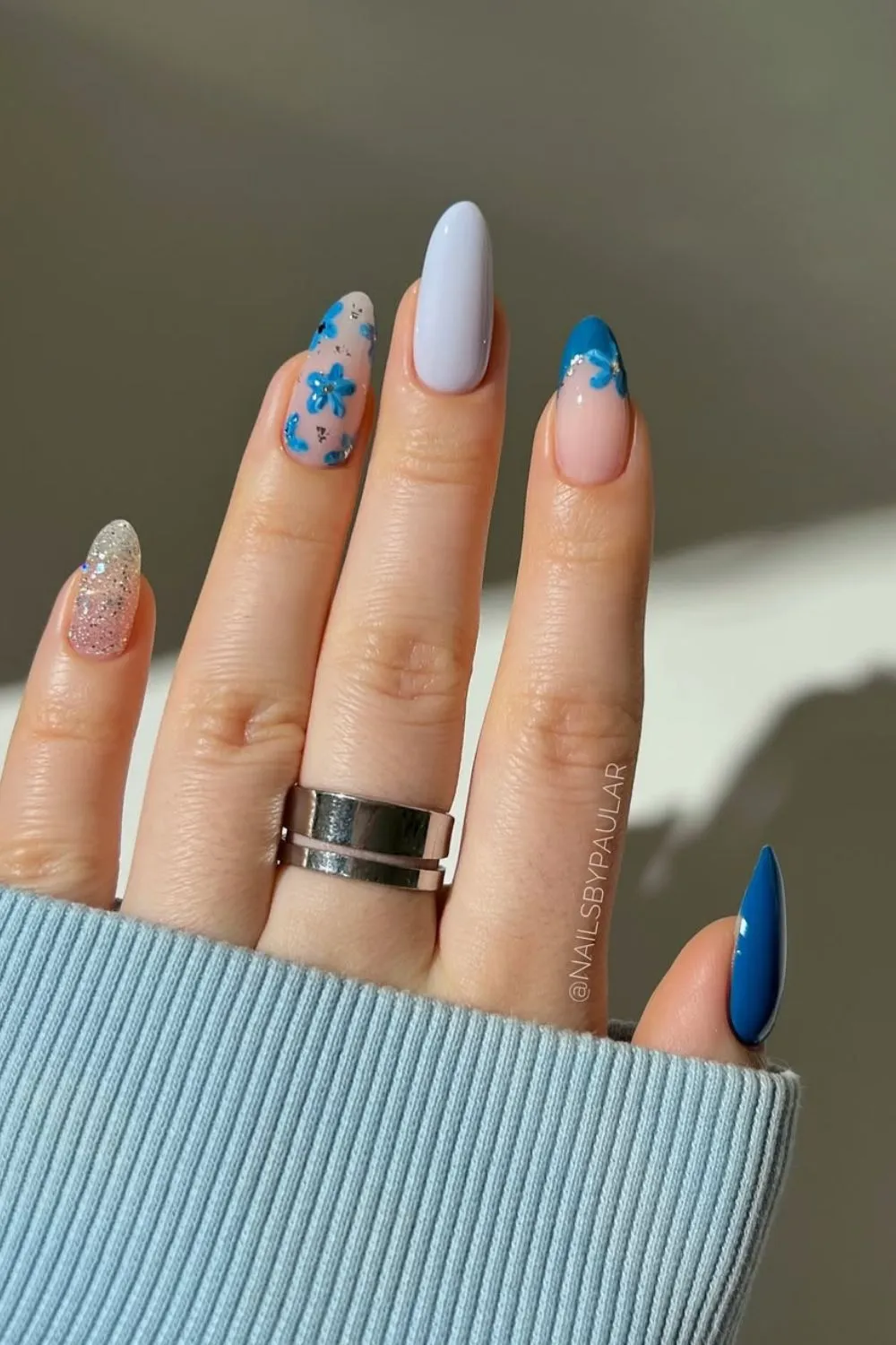 Floral Blue and Glitter Nail Art - Hand with mixed design of blue flowers, silver glitter, and solid blue nails