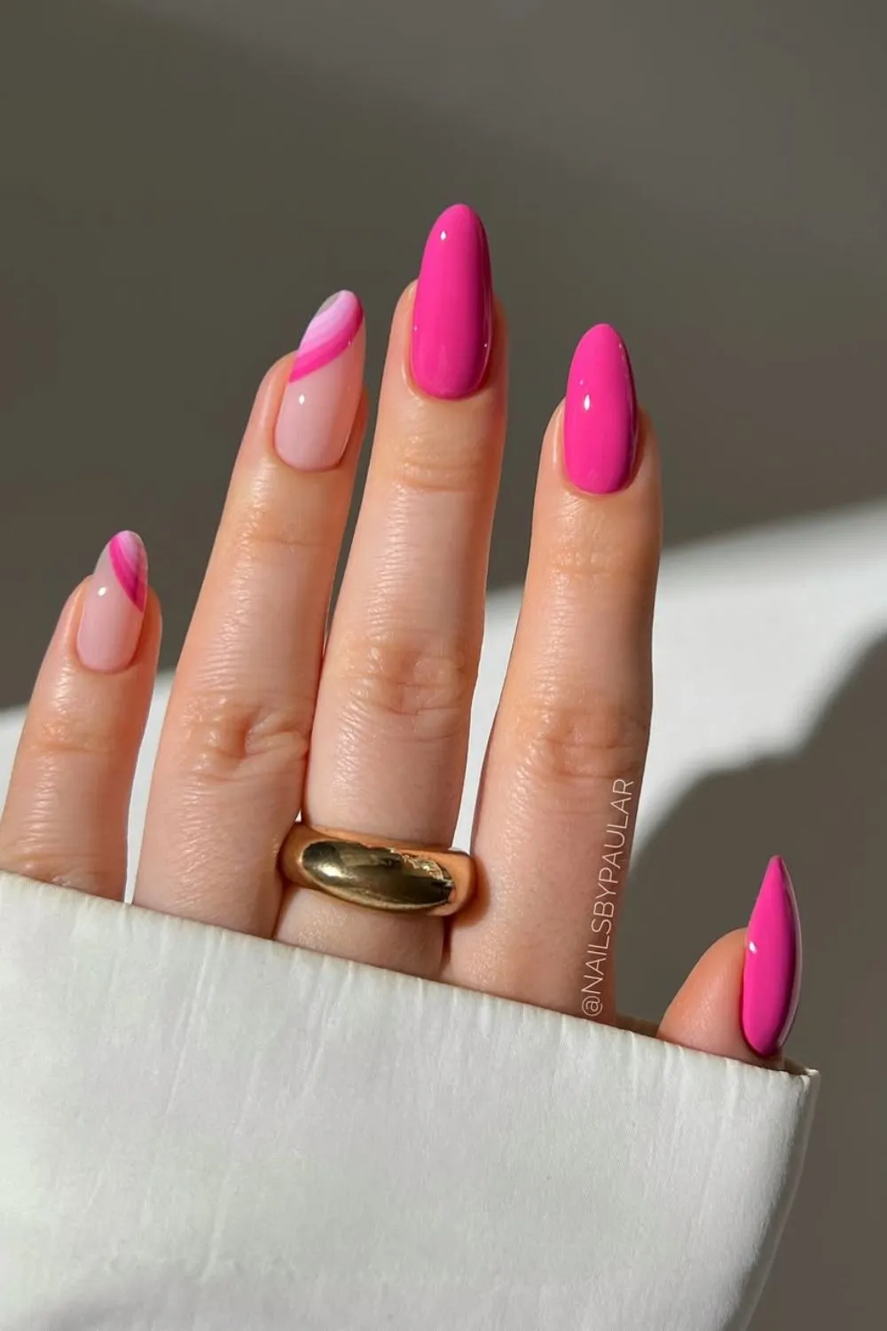 Bubblegum Pink Nail Design with Swirls - Hand with long almond nails painted in hot pink and accented with pink swirls on a nude base