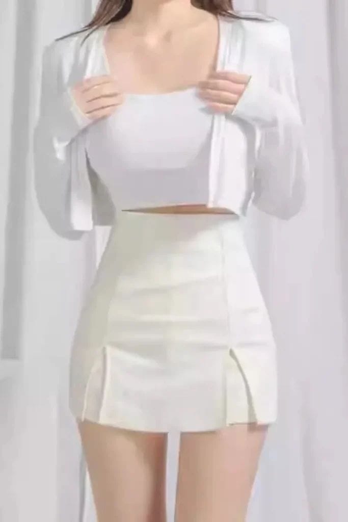 White Crop Top and Skirt Set - Woman in a casual white crop top, mini skirt, and matching cardigan set.