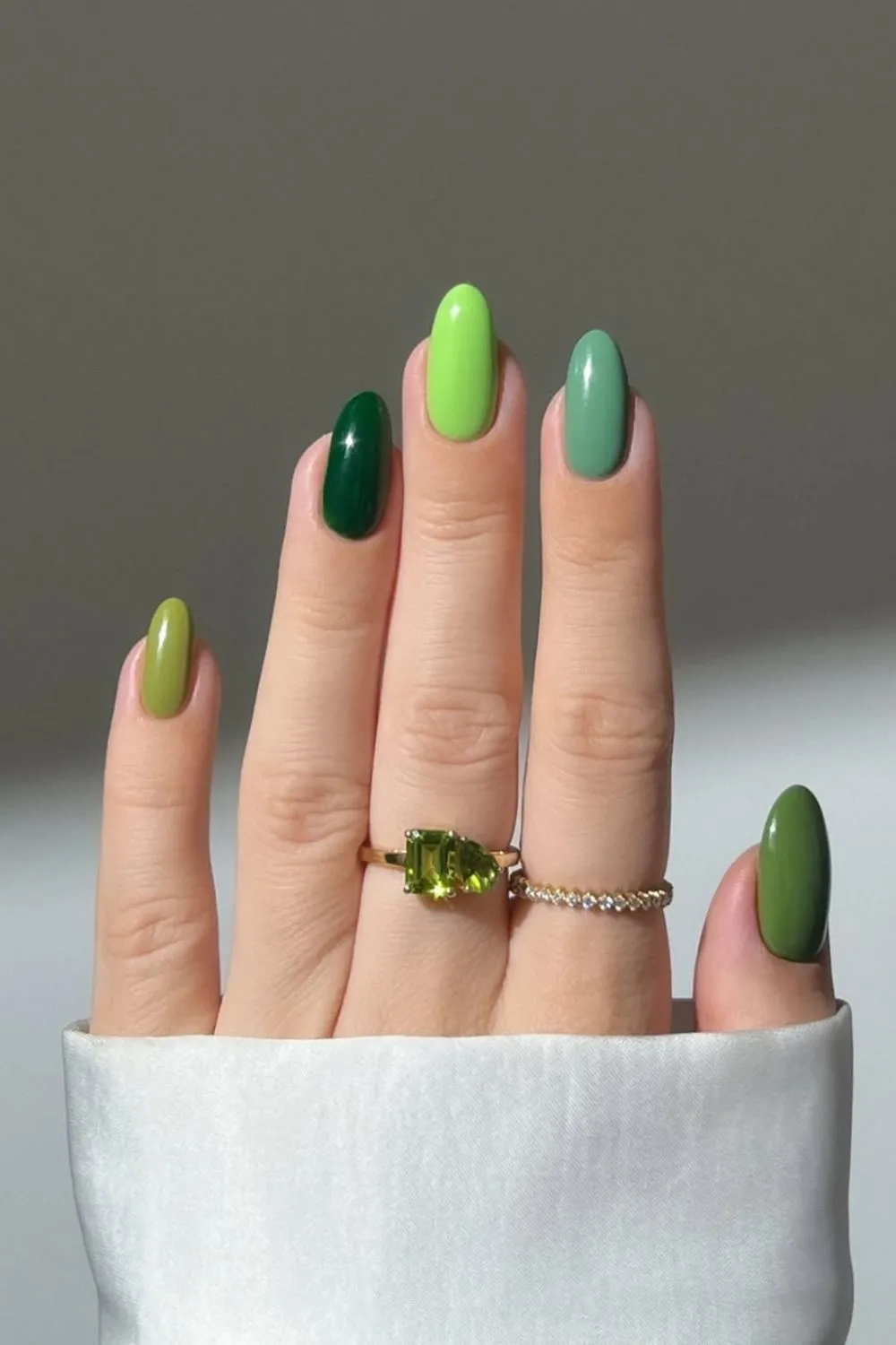 Green Gradient Skittles Nails - Hand with each nail painted in a different shade of green for a fun gradient effect