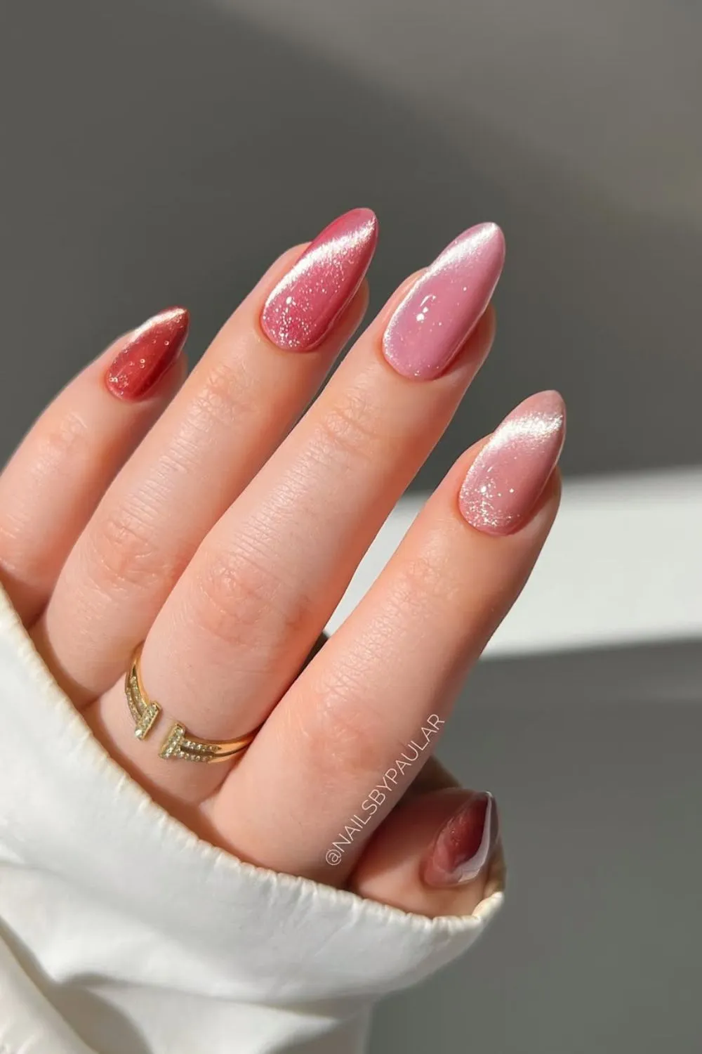 Pink Glitter Ombré Nails - Hand with nails transitioning from pink to red with a glitter ombré effect