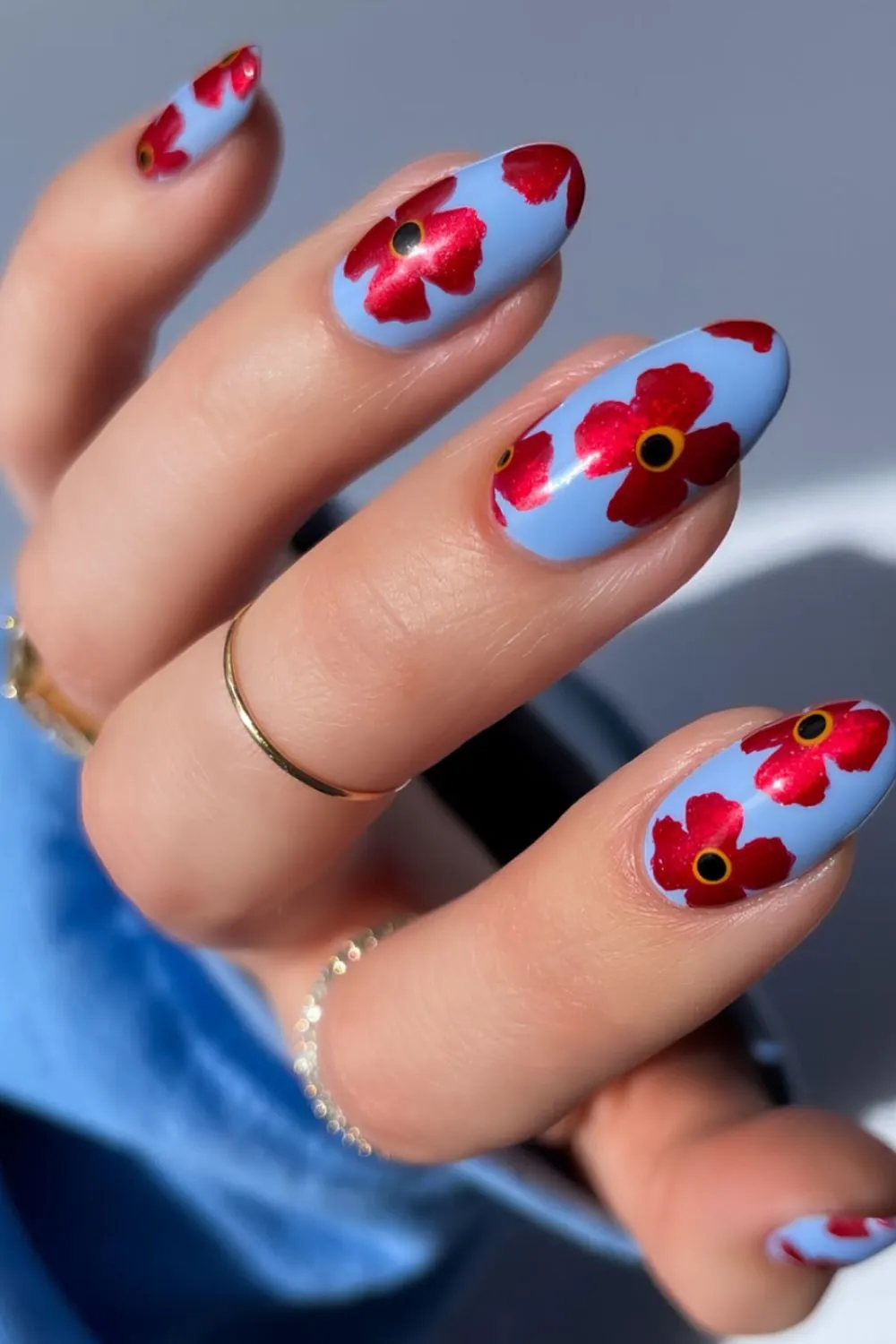 "Red Floral Art on Blue Nails - High Contrast Trendy Nail Design"