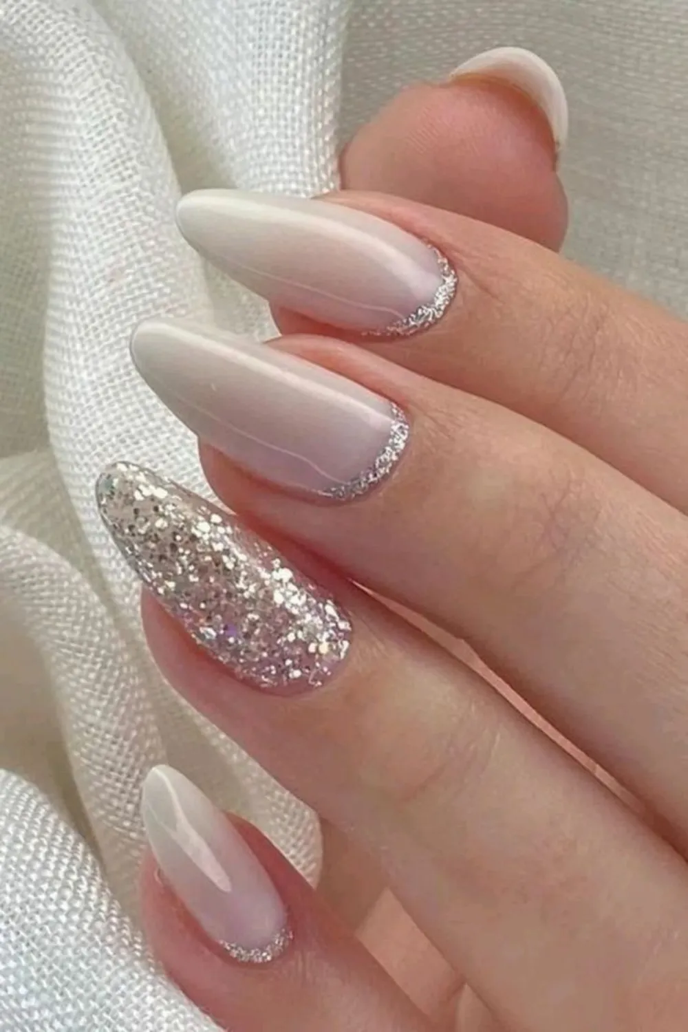 White Almond Nails with Silver Glitter Accent - Modern almond-shaped white nails featuring silver glitter tips and a statement nail