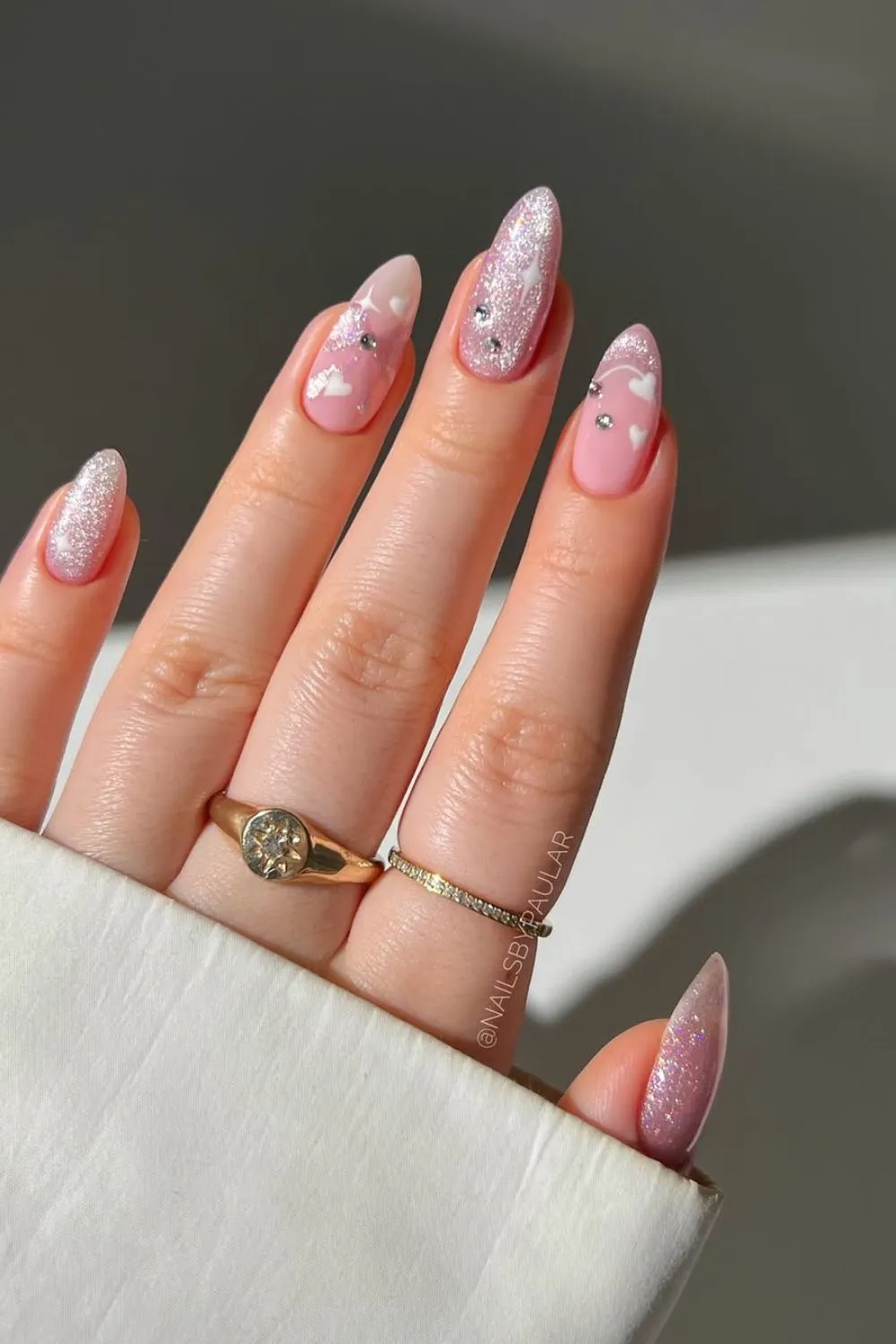 Romantic Pink Glitter and Heart Nails - Hand with pink glitter nails, heart shapes, and rhinestone embellishments