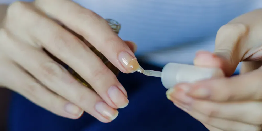A person applying a strengthening base coat 