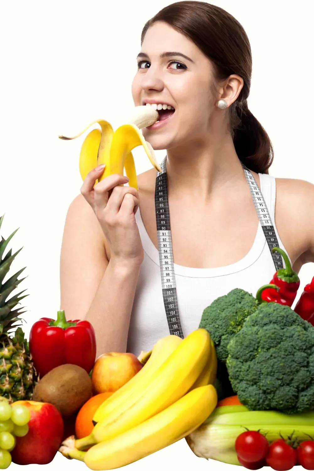 A woman eating a banana surrounded by fruits
