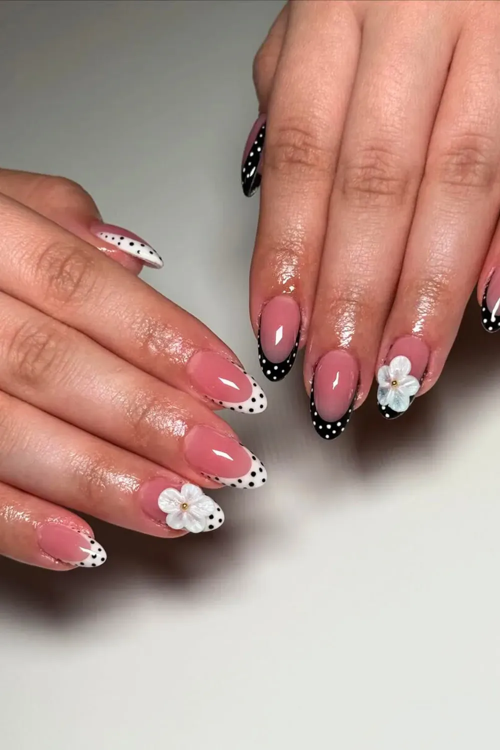 Black and White French Tips with Polka Dots and a Flower - Black and white French tip nails with playful polka dots and a white floral accent for a chic design
