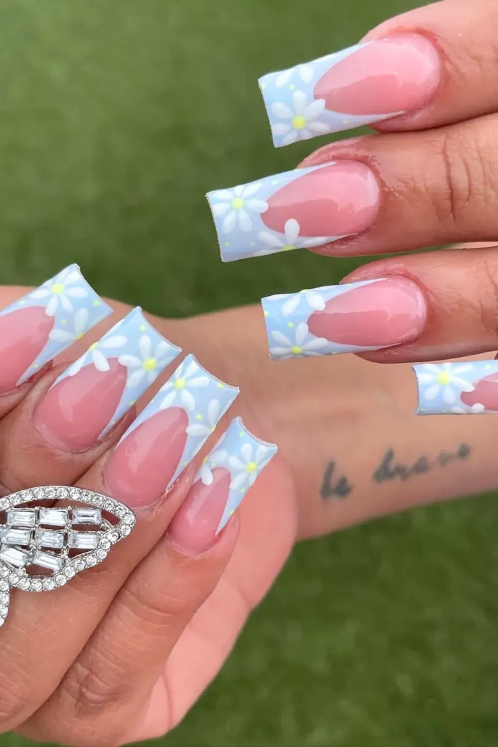 Blue French Tips with Daisies Alt Text: Light blue French tip nails with delicate white daisies for a soft, summery look