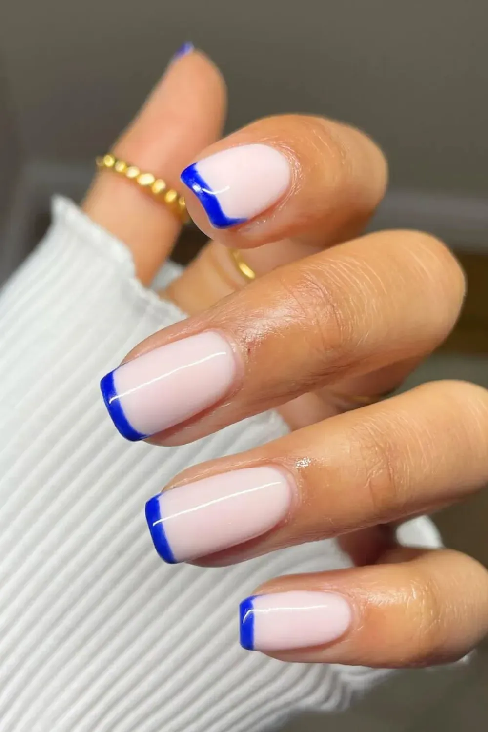 A stylish French manicure featuring a classic nude base with bold blue tips, offering a modern twist on the traditional design