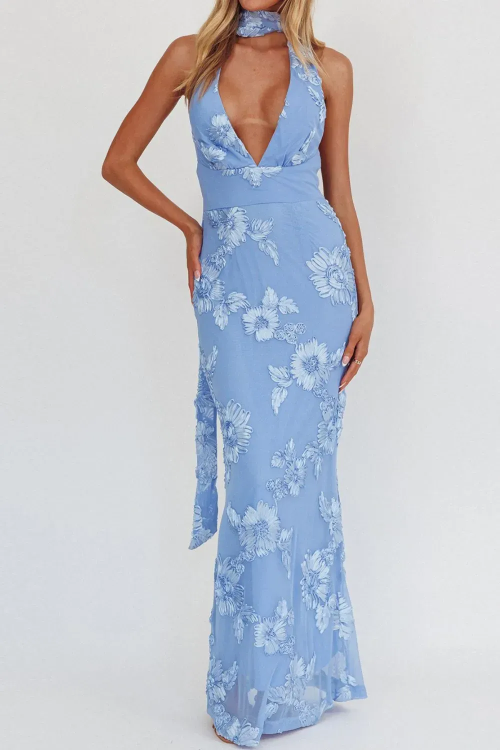 Woman in plunging blue halter floral dress with embroidered details.