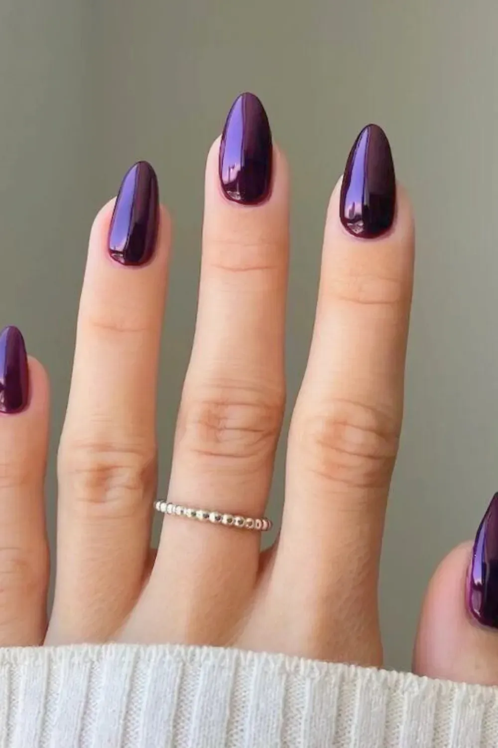 Glossy Burgundy Almond-Shaped Nails with Silver Ring - Close-up of almond-shaped nails painted in a glossy burgundy shade with a silver ring on one finger.