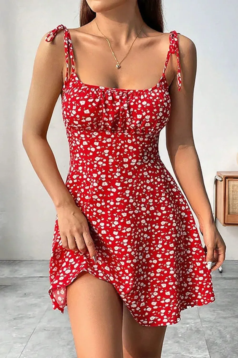 Woman in red floral mini dress with spaghetti tie straps and soft waves.