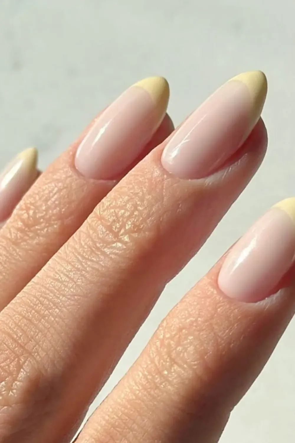Chic French tip nails with a neutral base and yellow tips, featuring a modern twist on a classic manicure