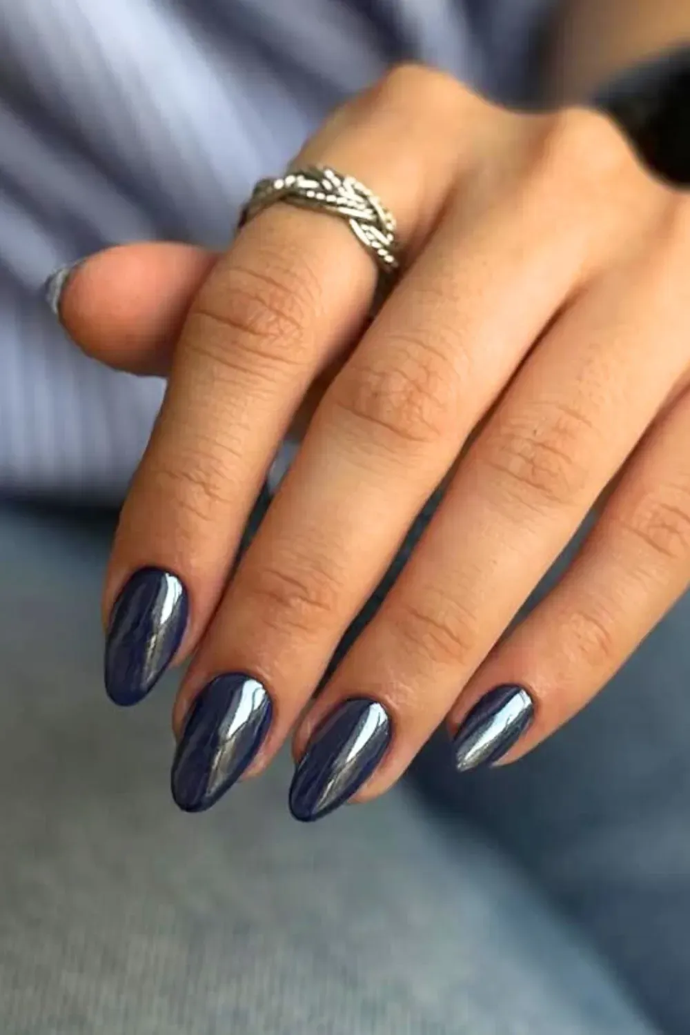 A hand with chrome blue nails, glowing with a futuristic shine.