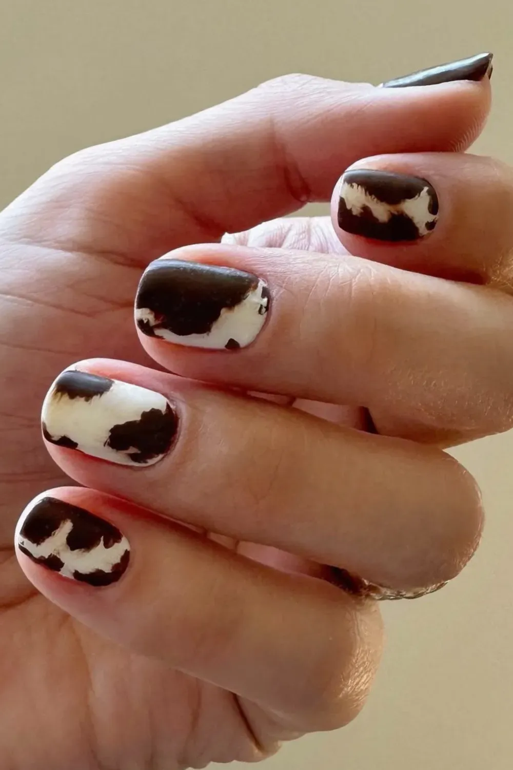 Trendy cow print nails featuring brown and white spots for a bold look