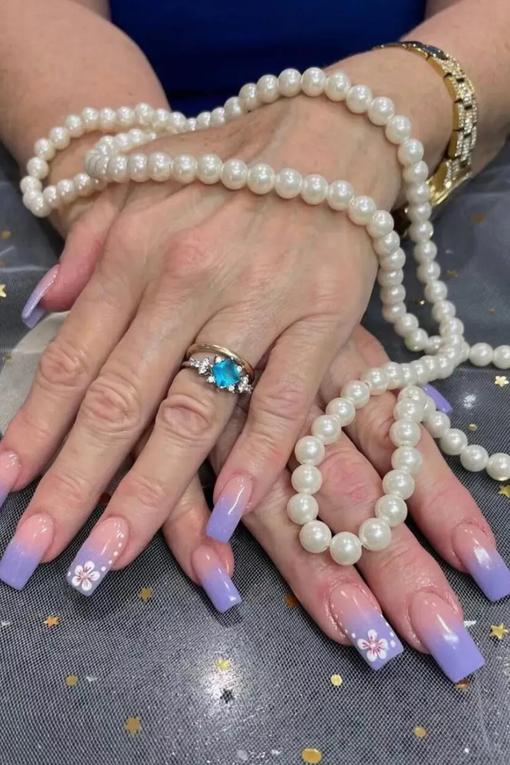 Purple and blue ombre nails adorned with flower art