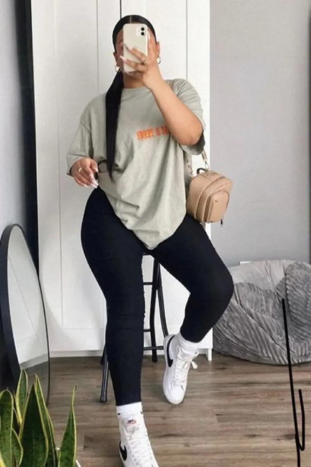 Casual Yet Chic with Loose Tee - A woman wearing a loose graphic tee and black leggings, styled with sneakers