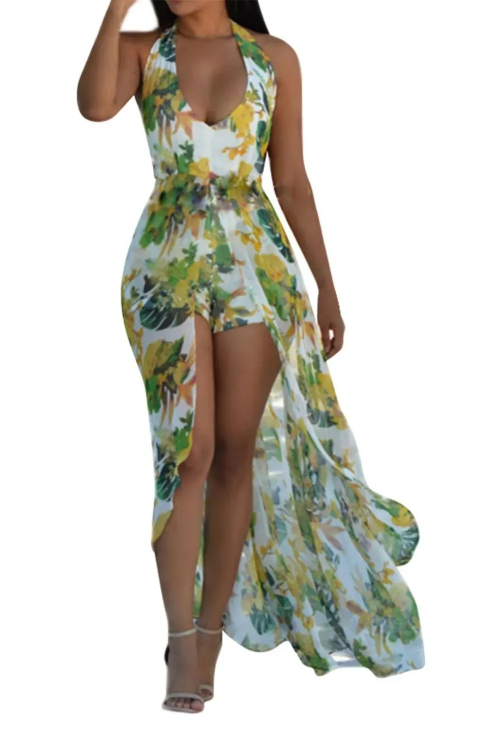 Woman in yellow tropical floral romper with sheer maxi overlay walking confidentl