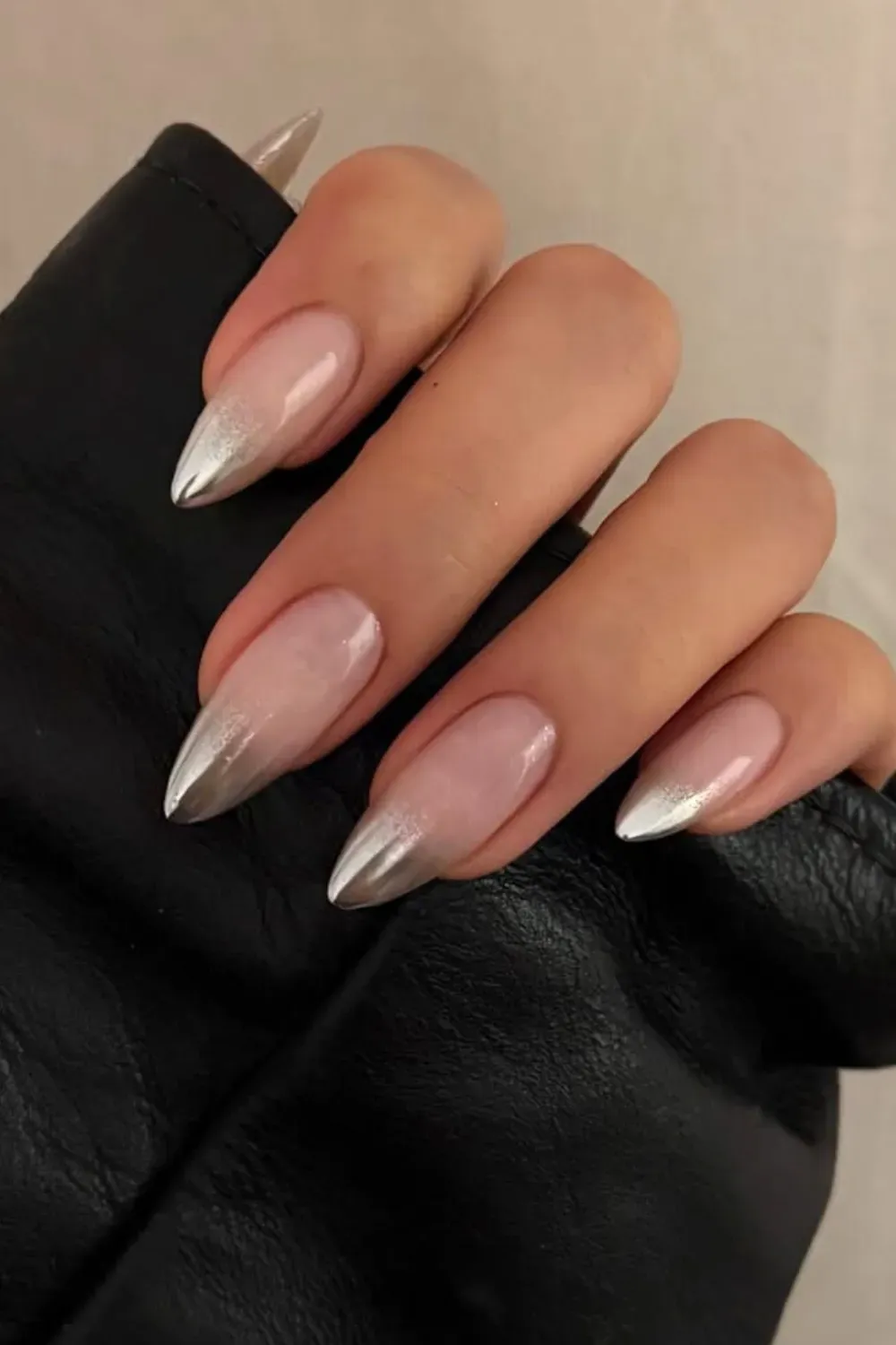 A hand with subtle silver ombre nails that transition from nude to a shimmering silver.