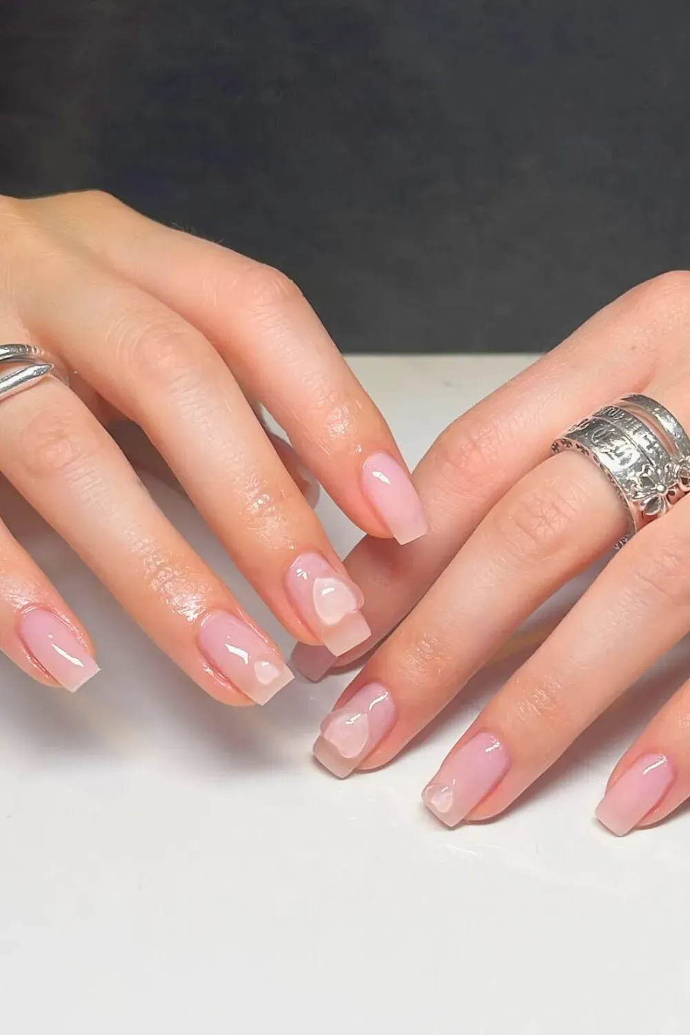 Minimalistic square nails featuring subtle 3D heart designs for a clean and charming look