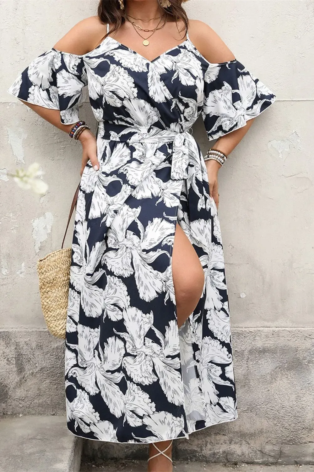 Woman in black and white floral wrap dress with slit and off-shoulder sleeves.