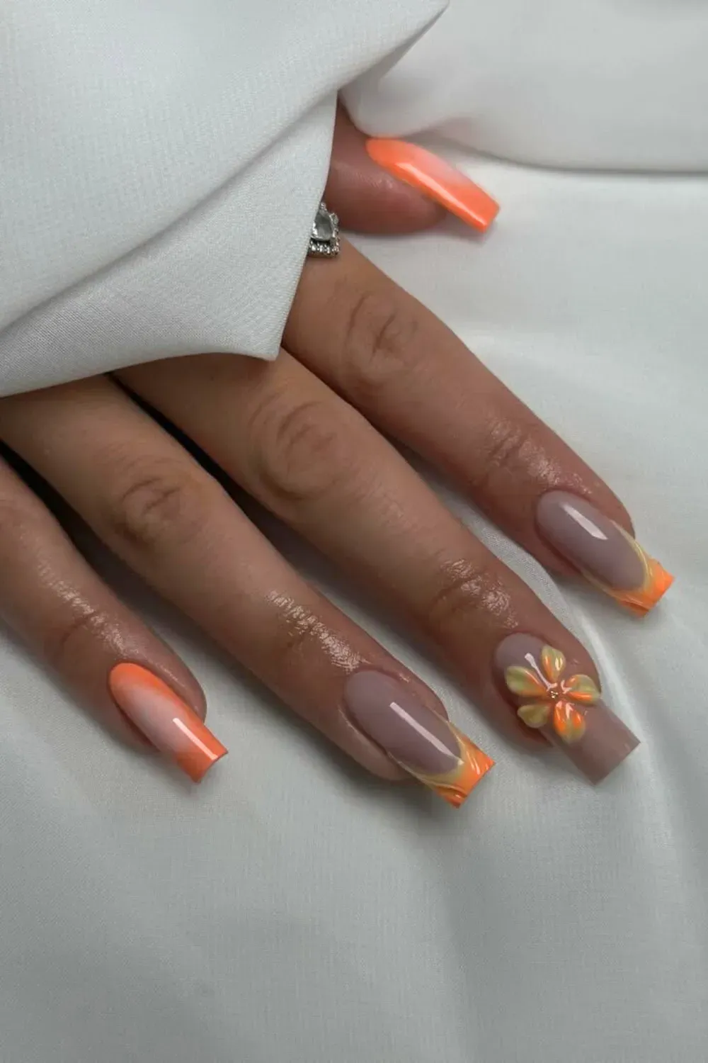 Orange and Pink French Tips with Floral Accent Alt Text: Bold orange and pink French tips with a vibrant flower accent on the ring finger