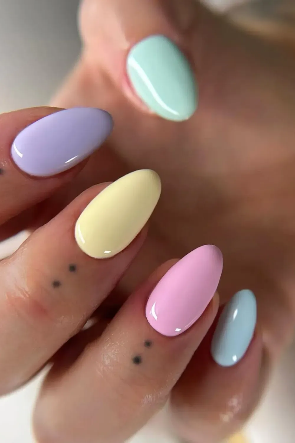 Pastel rainbow nails in shades of lavender, mint green, yellow, and pink for a playful look