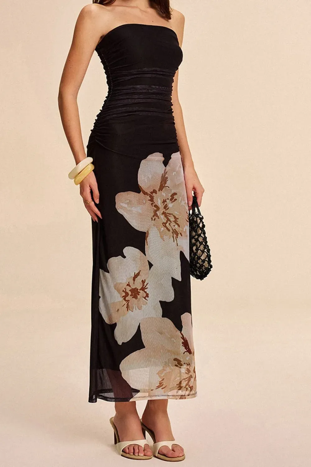 Woman wearing a strapless sheer floral print dress with white sandals.