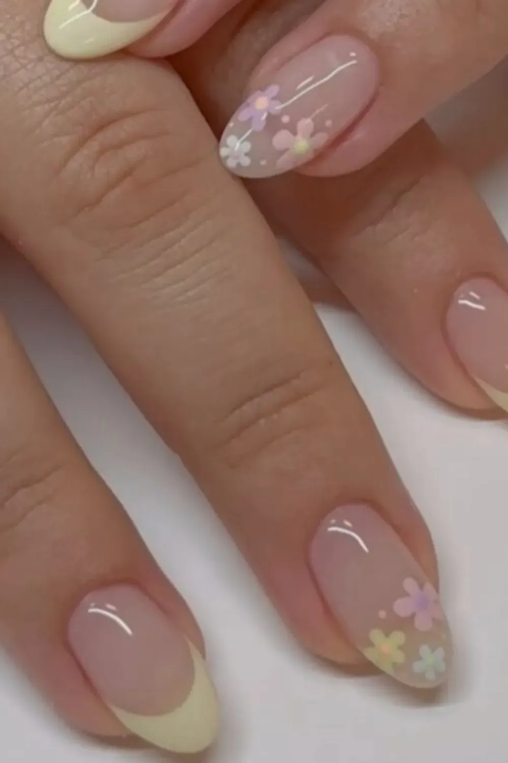 Pastel yellow French tips with colorful floral designs for a cute back-to-school look