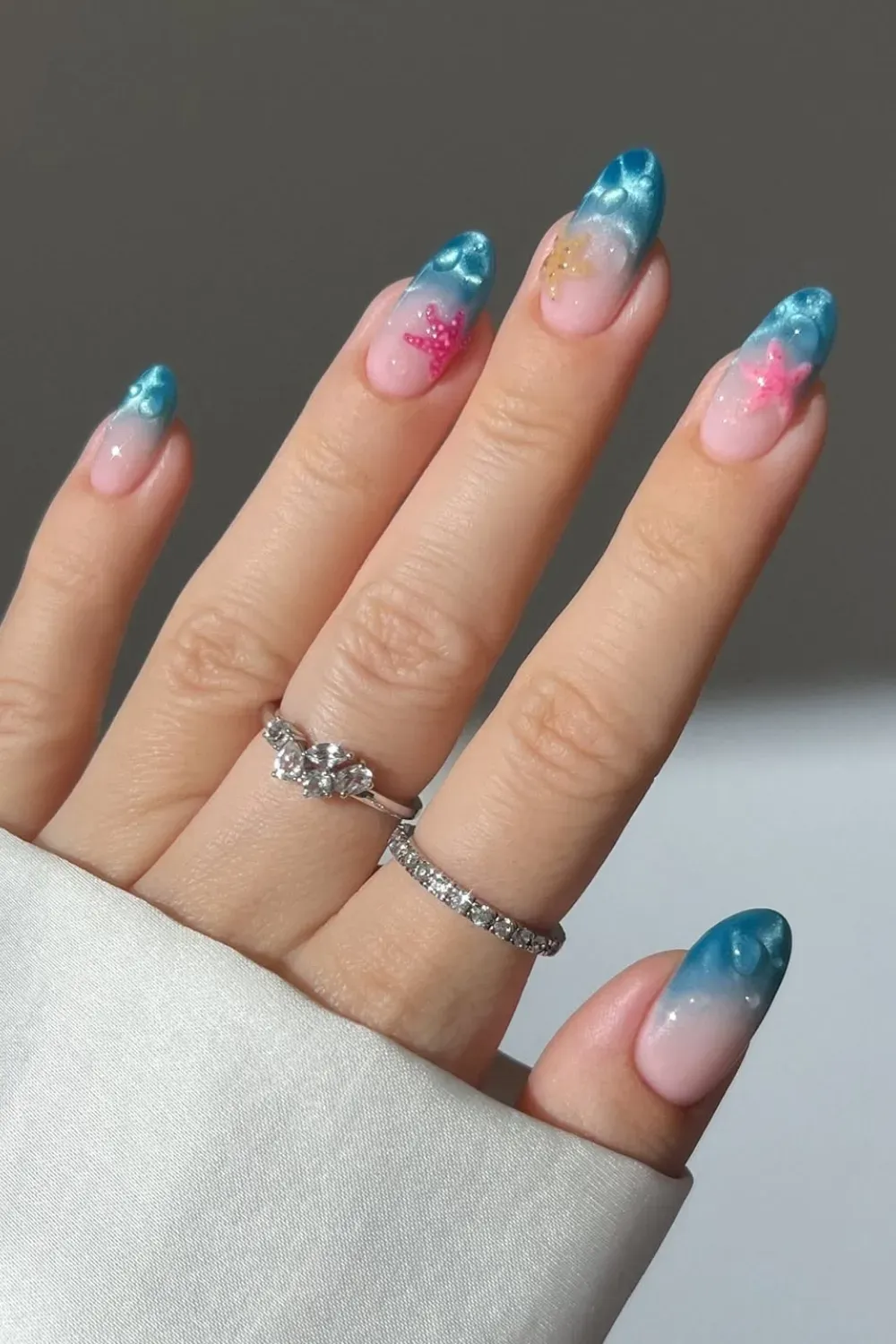 Glamorous ombre nails with sea-inspired designs and starfish for a soft yet elegant beach look