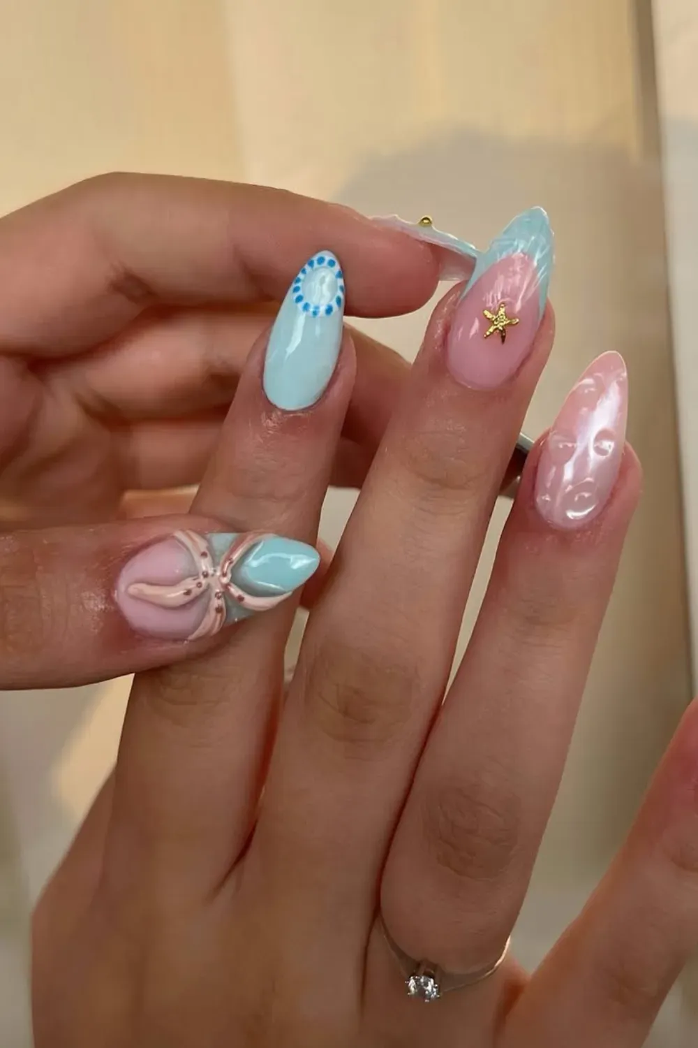 Soft pink and blue nails with starfish and intricate designs for a delicate summer look