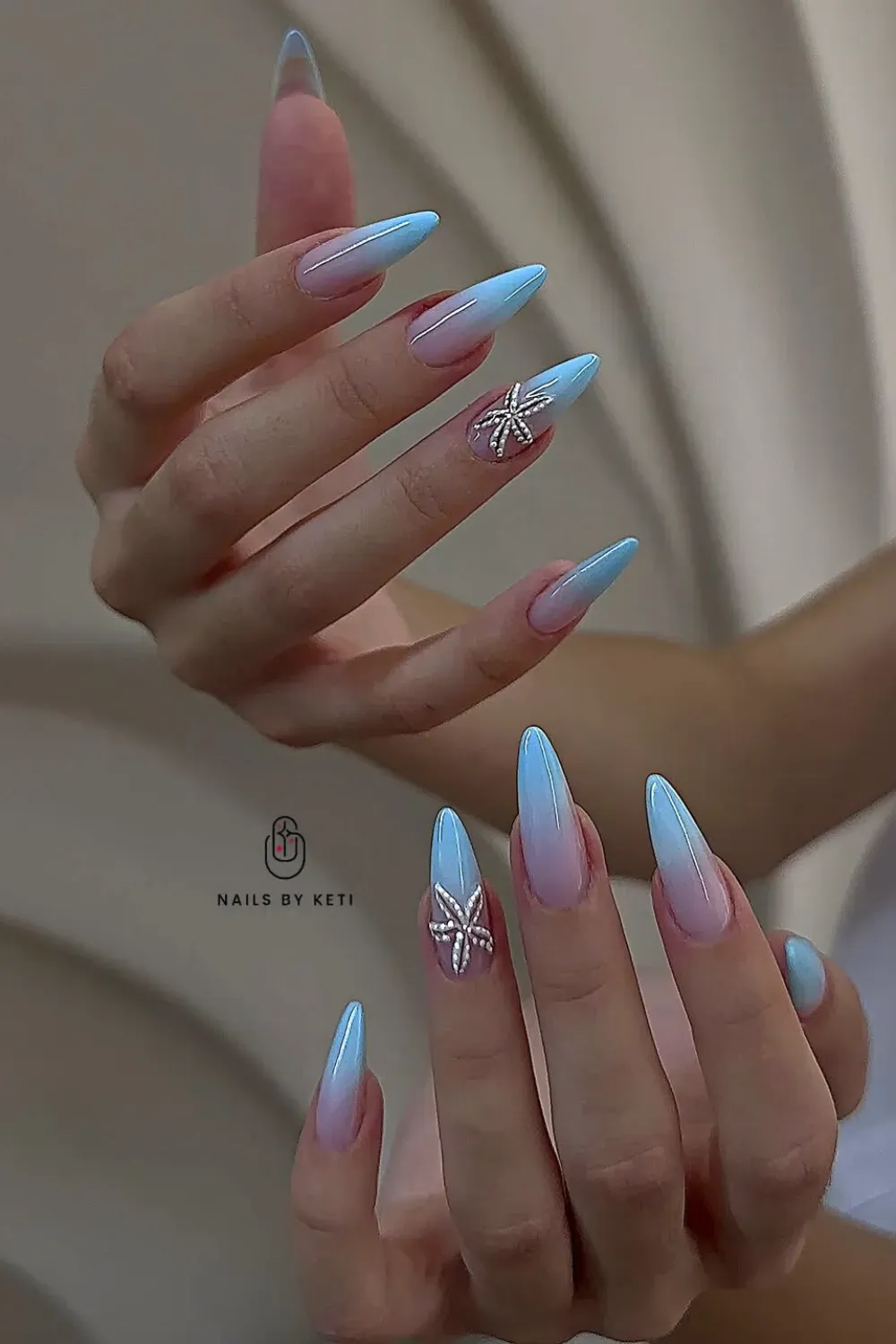 Stiletto nails featuring pink and blue ombre with butterfly accents