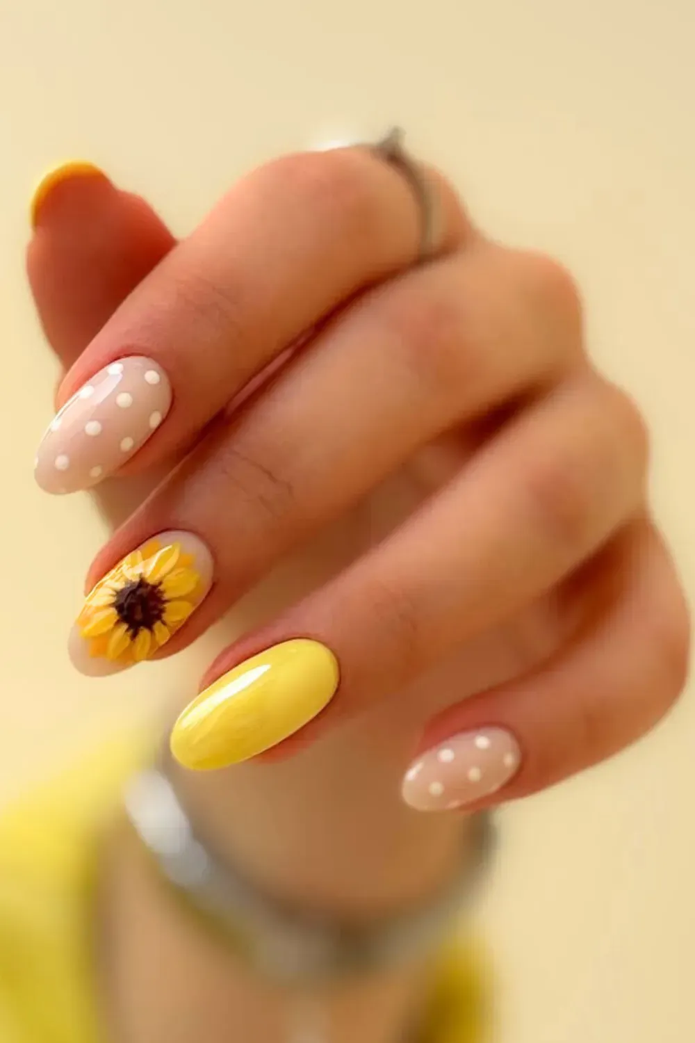 A hand with yellow sunflower nails, perfect for the summer season