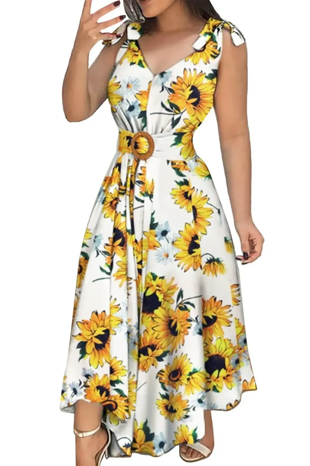 Woman in a white midi dress with bold sunflower prints and a belted waist, styled with white heels.