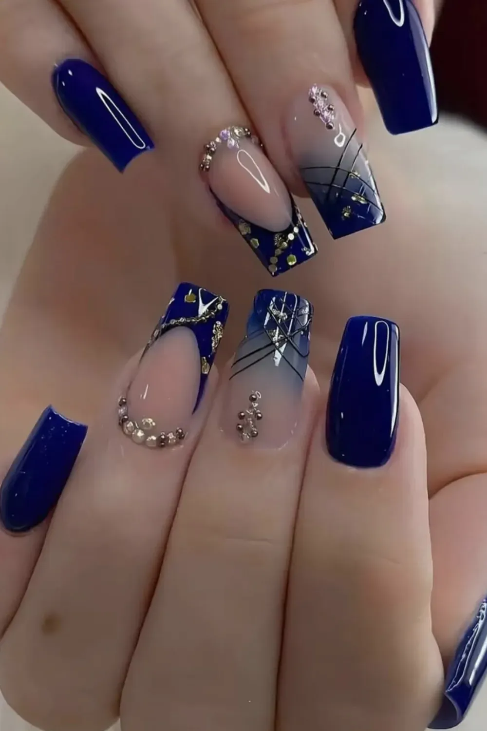 Jewel-Like Blue with Gems and Stripes - Swirling blue nail art with dynamic patterns and gold accents
