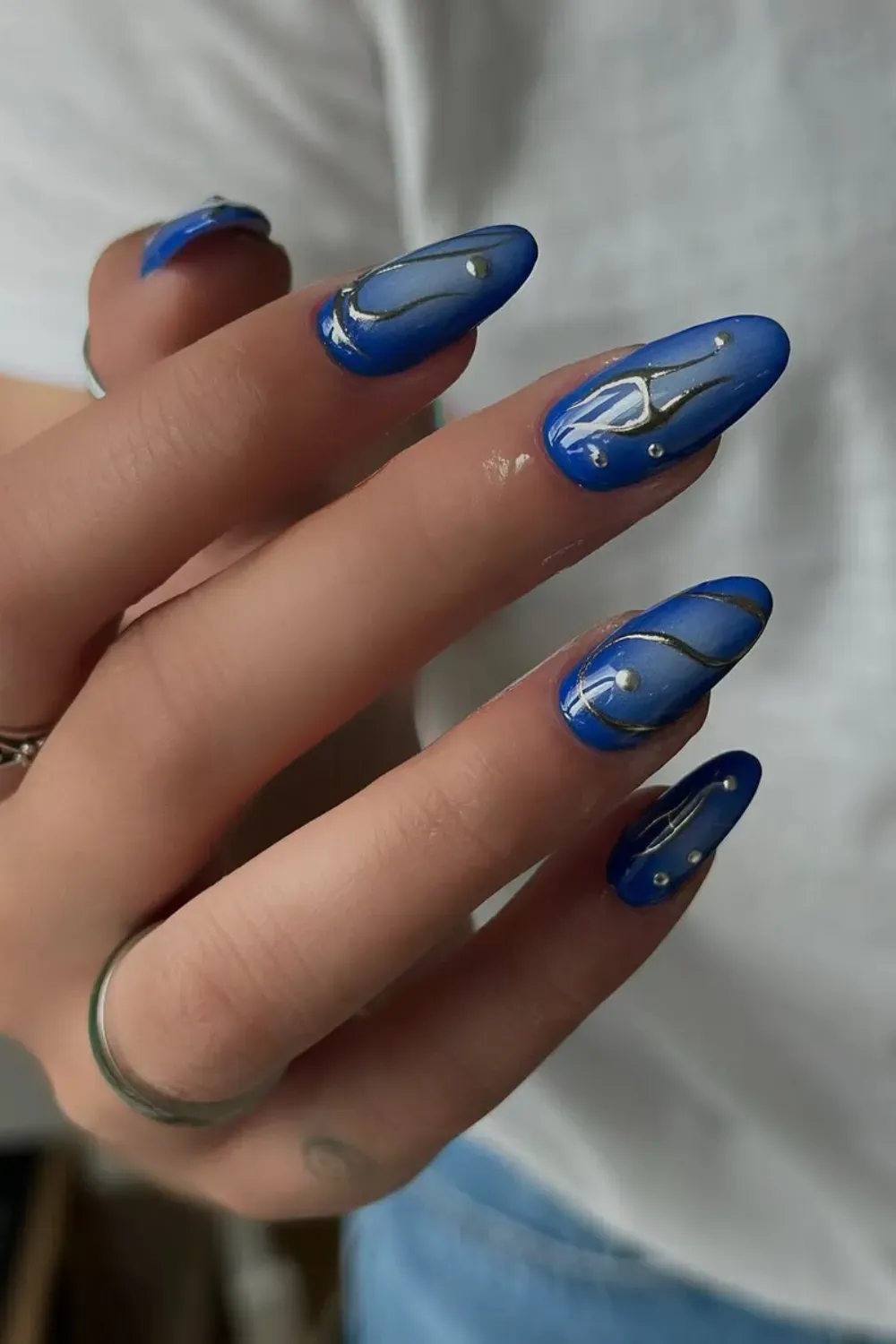 Artistic Blue Swirls with Pearl Accents - Dark blue nails paired with white designs, including geometric shapes