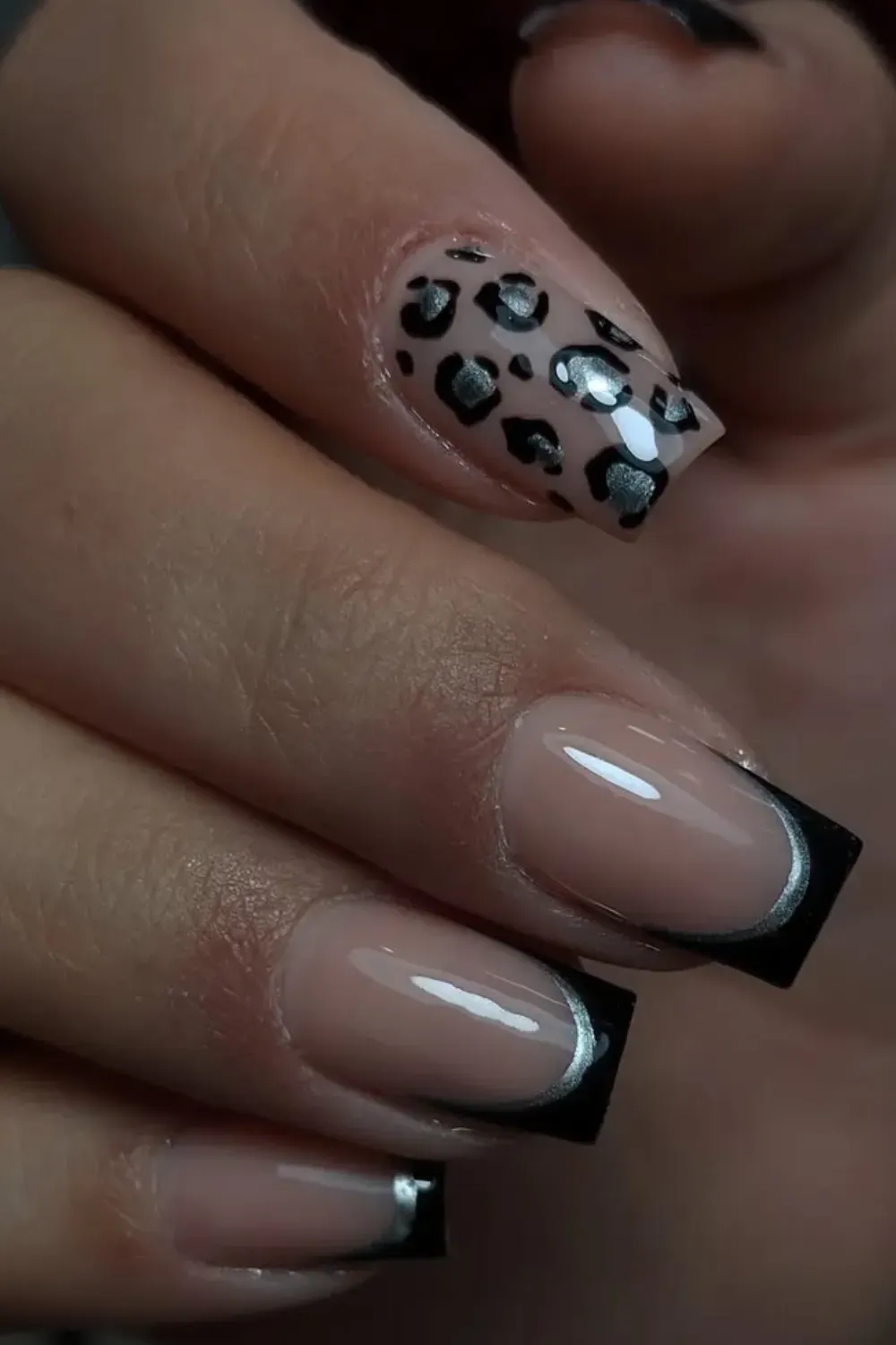 Black French tips with a silver metallic line, accompanied by a leopard print accent nail, creating a bold and chic look