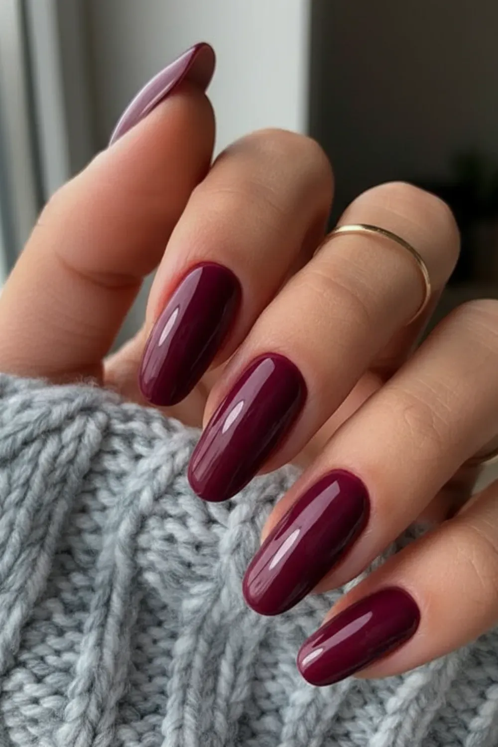 Glossy Burgundy Wine Nails - A close-up of a hand with glossy, almond-shaped nails painted in a mix of burgundy and wine red shades, with some nails featuring a gradient and others having gold foil accents