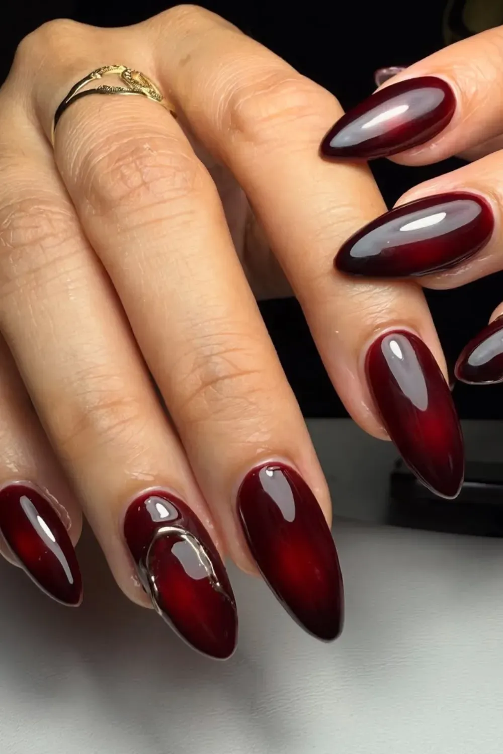 Deep Burgundy Nails with Metallic Gold Design - Elegant deep burgundy nails enhanced with metallic gold swirls for a gothic Halloween look.