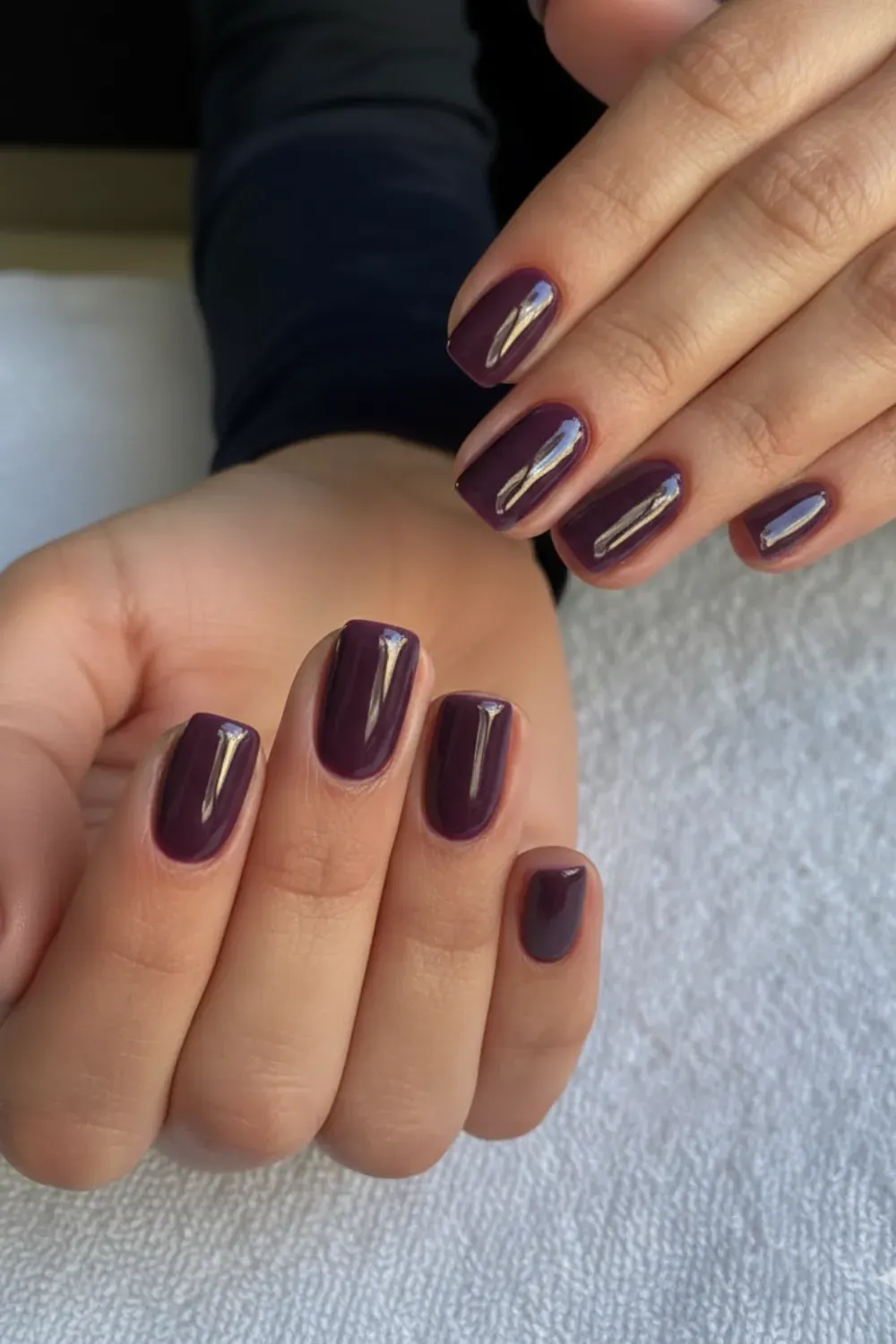 Glossy Deep Plum and Eggplant Nails - A close-up of a hand with glossy, squared nails painted in a solid deep plum or eggplant color