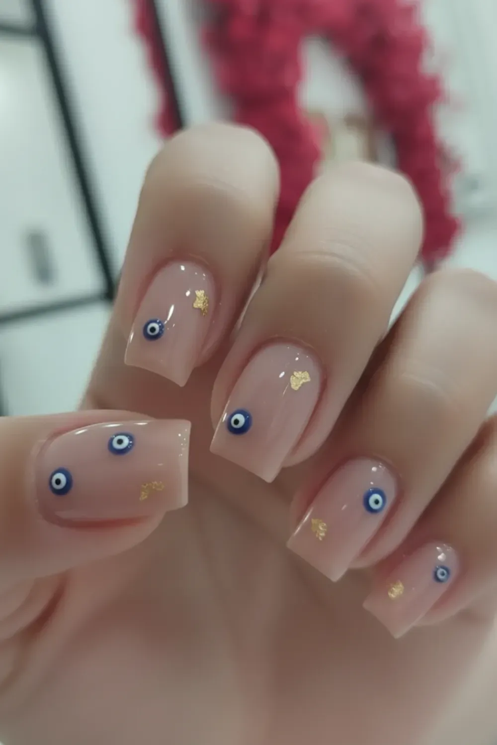  Short nude nails adorned with evil eye symbols and gold accents, offering a unique, trendy look.