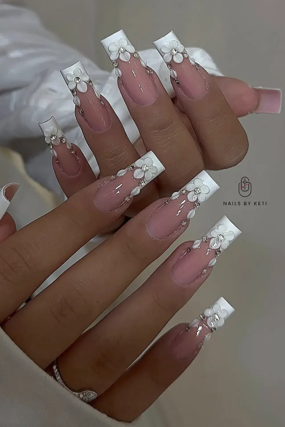 Floral French Tips - French tips adorned with delicate white floral accents, creating a romantic and feminine look.
