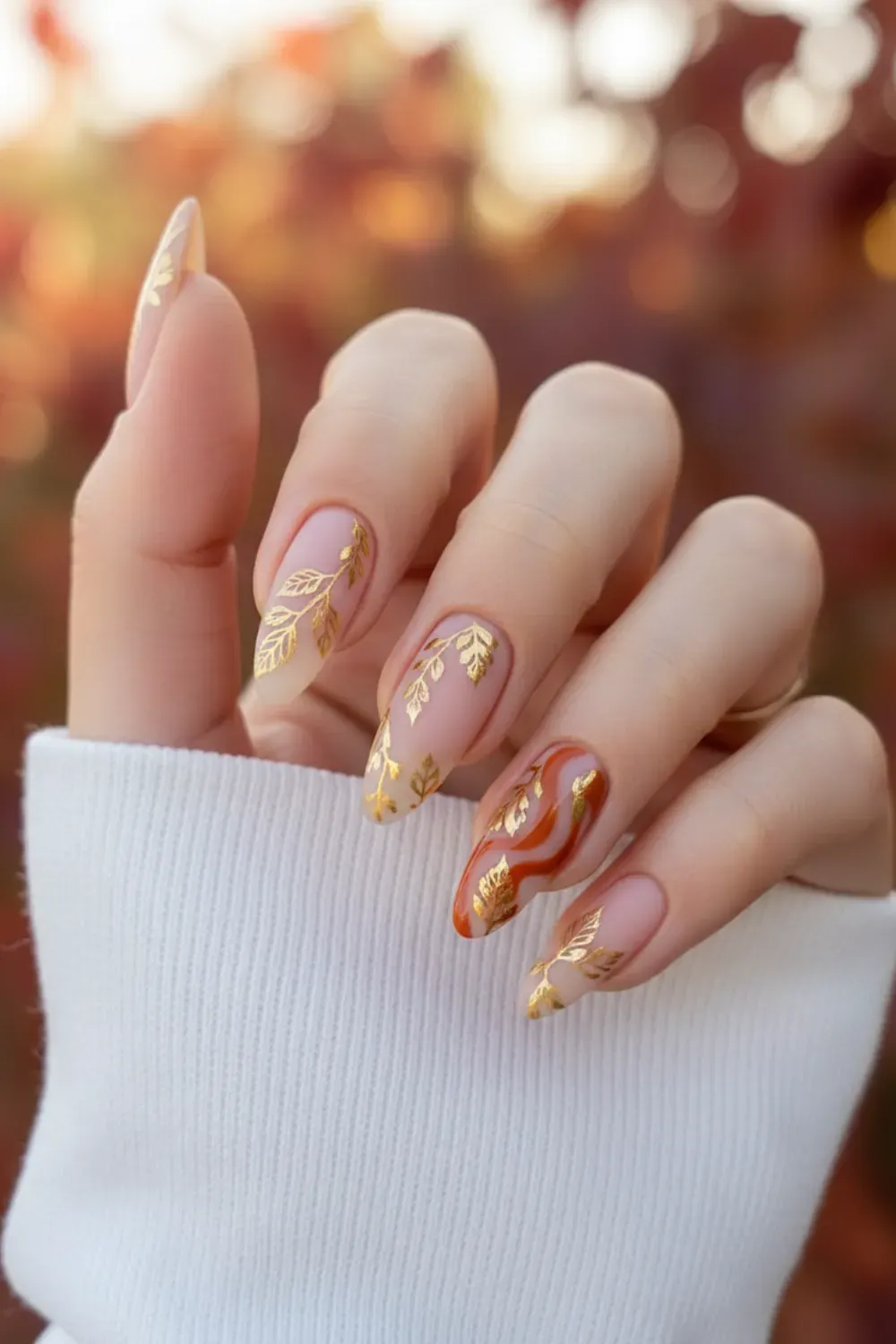 Golden Leaf Nail Art - Autumn-inspired golden leaf designs on beige nails for a chic fall look
