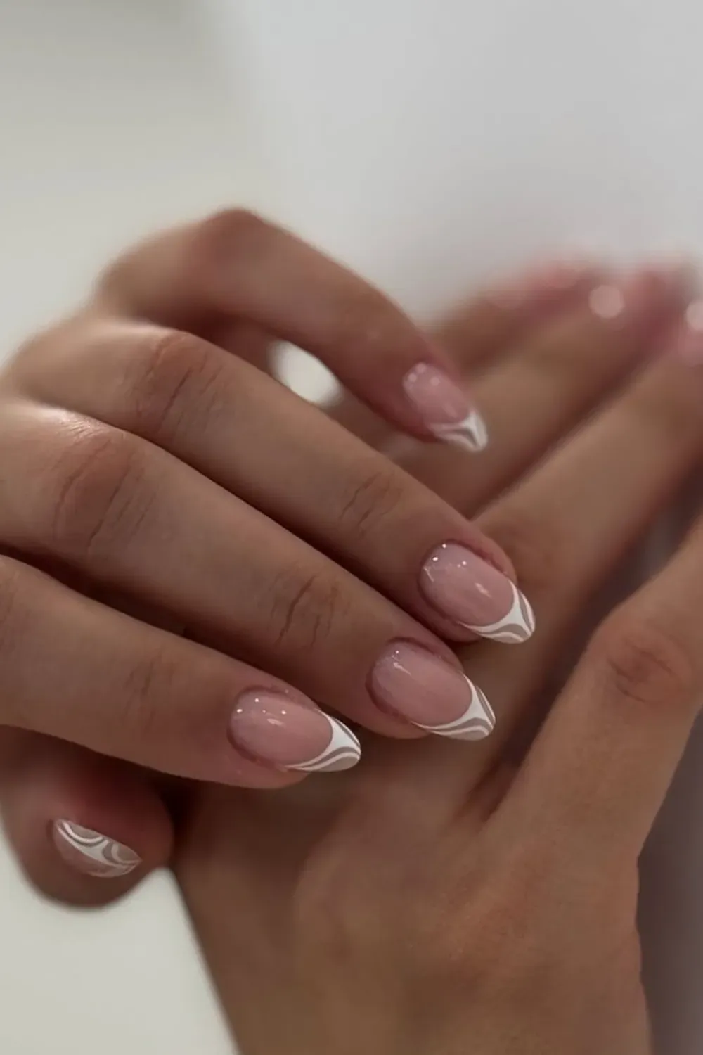 White Swirl French Tips - Nude French tips with delicate white swirls at the tips, creating a sophisticated and artistic design with a modern twist.
